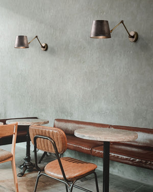 Two adjustable industrial wall light with a pre aged finish displayed in a cafe 