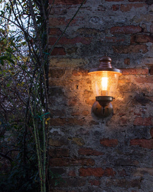 Metal and glass wall light placed outside on a brick wall
