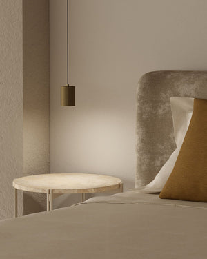 Neatly made bed with a side table and pendant light in a neutral-toned room.