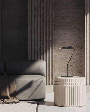 Modern interior with a grey sofa and decorative side table against a textured wall.