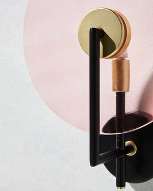 Decorative wall sconce with gold and black design on a light pink background