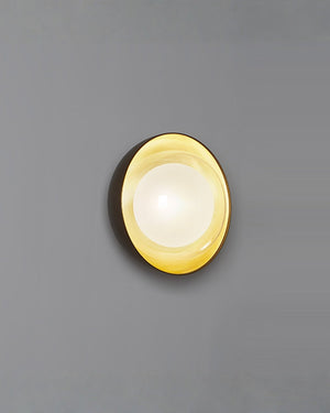 Round wall light fixture with gold rim on a gray background