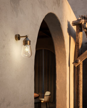 Mini Antique Brass Wall Light Outside a rustic house at golden hour