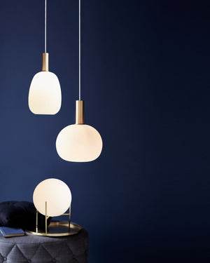 Three modern pendant lights against a dark blue wall.