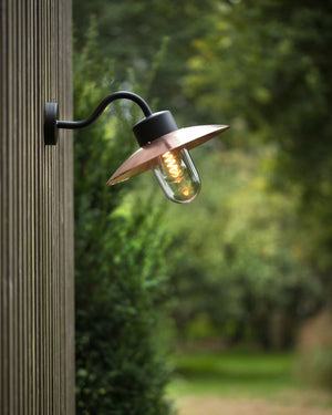 Outdoor wall light fixture on a wooden post with a blurred natural background