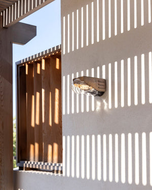 Modern outdoor wall light fixture on a textured wall with geometric patterns.