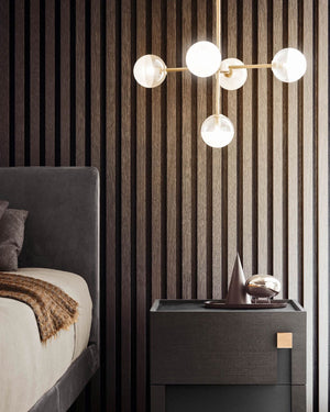 5 light modern chandelier placed next to a bed over a bedside table