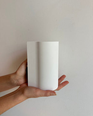 A pair of hands holding a plain white cylindrical wall light