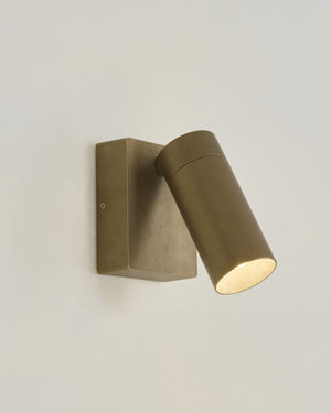 Outdoor brass accent wall light with warm light on mounted on a white wall