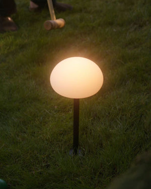 Glowing Ovate Portable Garden Spike on grass with a croquet set in the background - Lighting Collective 