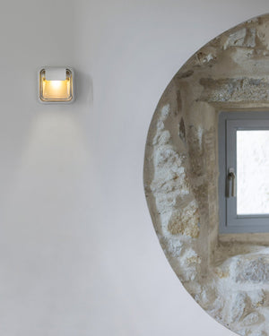 Recycled glass outdoor wall light in white mounted on rendered stone wall beside circular arched porthole window