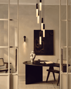Modern interior design with a round black table, chairs, and Reeded Glass and Brass Cylindrical Chandelier Pendant
