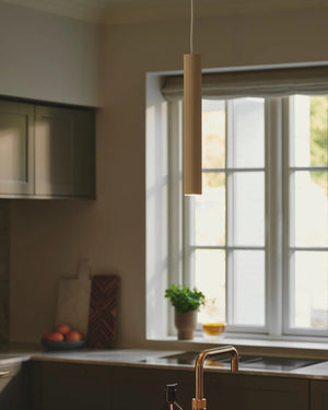 Modern kitchen with a sink and countertop, featuring the beige Reeded Metal Vertical Pendant - Lighting Collective 