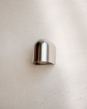 A small rounded stainless steel indirect step lighting fixture mounted on a textured white wall