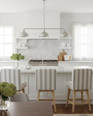 Modern kitchen with marble countertops, striped chairs, and a vase of flowers.