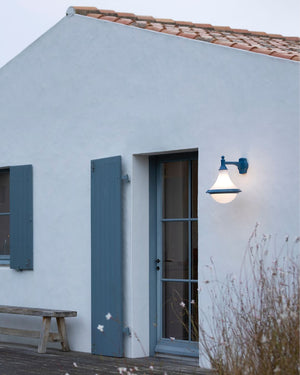 Downwards facing teardrop shaped wall light in steel blue finish on outdoor wall