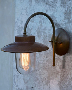 Pre-aged brass wall light on a grey exterior wall