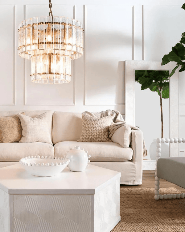 Modern living room with a beige sofa, decorative pillows, and a Two-Tiered Textured Crystal Chandelier | Lighting Collective