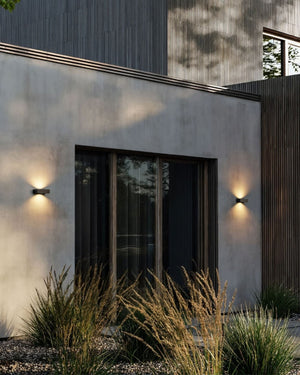 2 lit up modern up down coastal grade slim wall lights mounted on a textured wall outdoor entryway