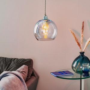 glass and silver metal spherical pendant with topaz blue finish beside a sofa light on