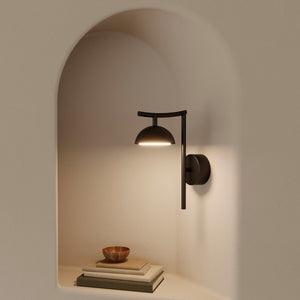 minimalist steel dome wall light in a beige interior room lightening up a few books